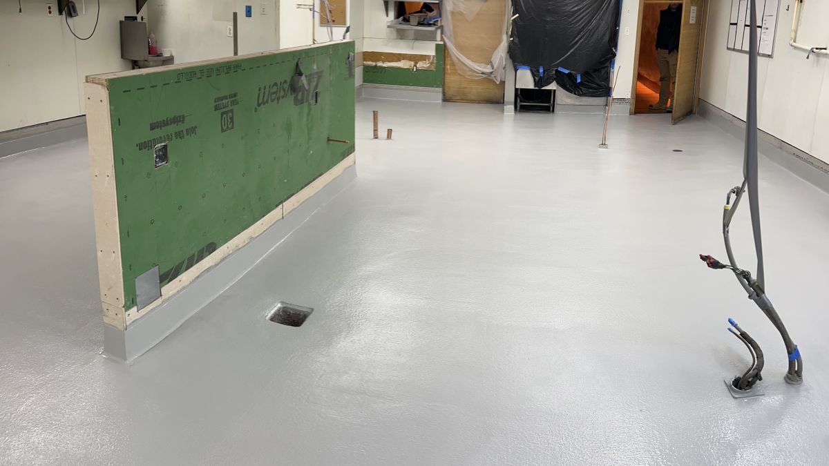Industrial kitchen flooring installation in Morristown, NJ, featuring a seamless gray urethane cement finish and integrated sanitary coving.