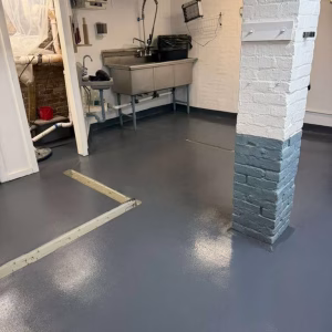 Commercial kitchen epoxy flooring installation featuring a seamless grey floor finish around a structural column in a New Jersey restaurant